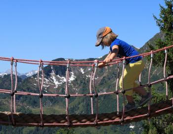 A small child in a helmet on a swinging bridge
