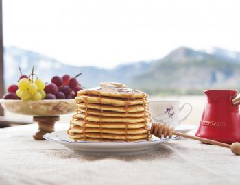 A plate of pancakes and fruit in front of the mountains