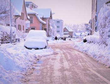 Snow covered road with a vehicle stuck under lots of snow