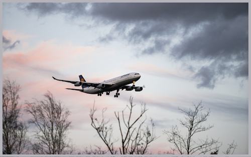 A white plane flying above a cloudy sky